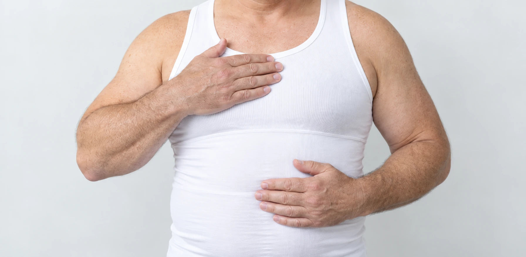 Older male model wearing the white InShape tank, with one hand across his chest and one across his stomach.